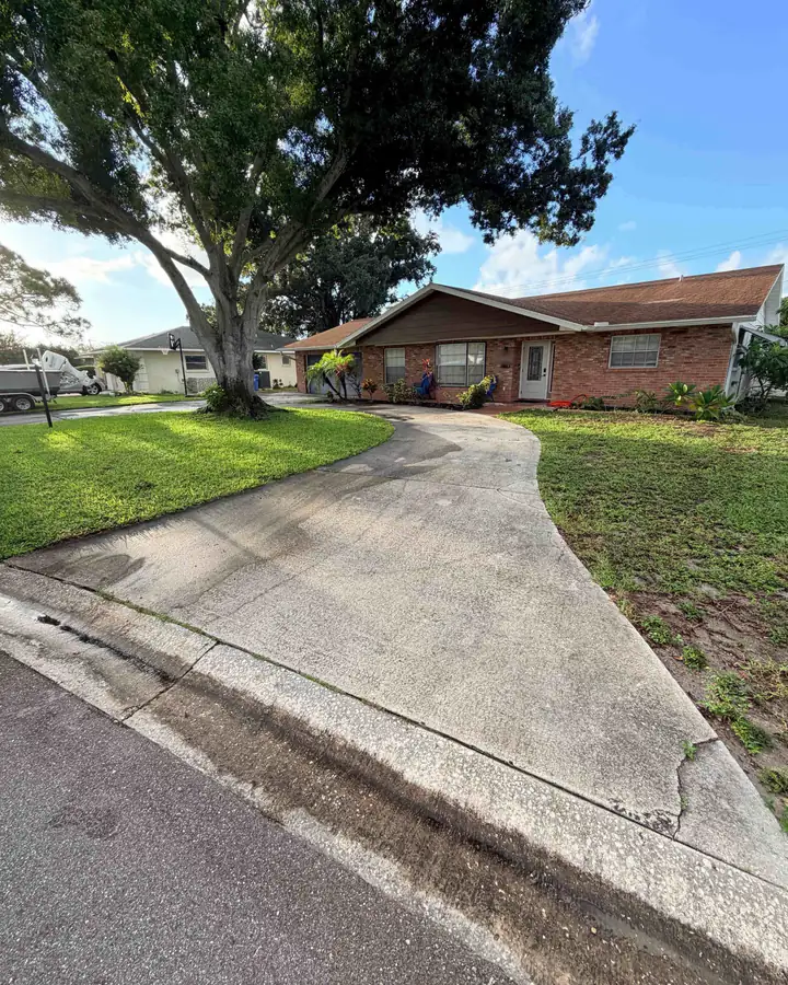 The same Bradenton driveway before pressure washing: gray, stained, and streaked